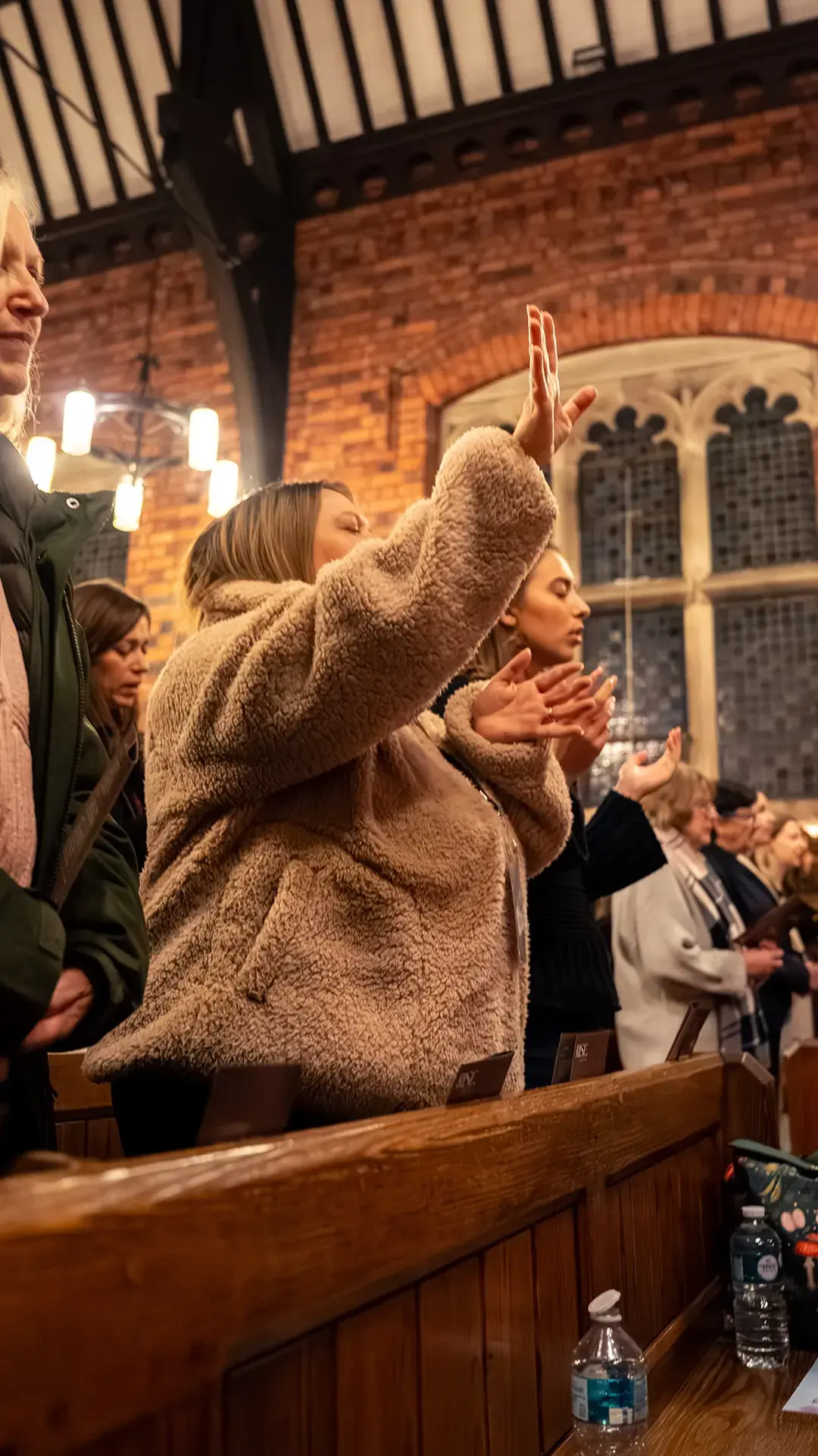 Women worshipping with hands raised in a church